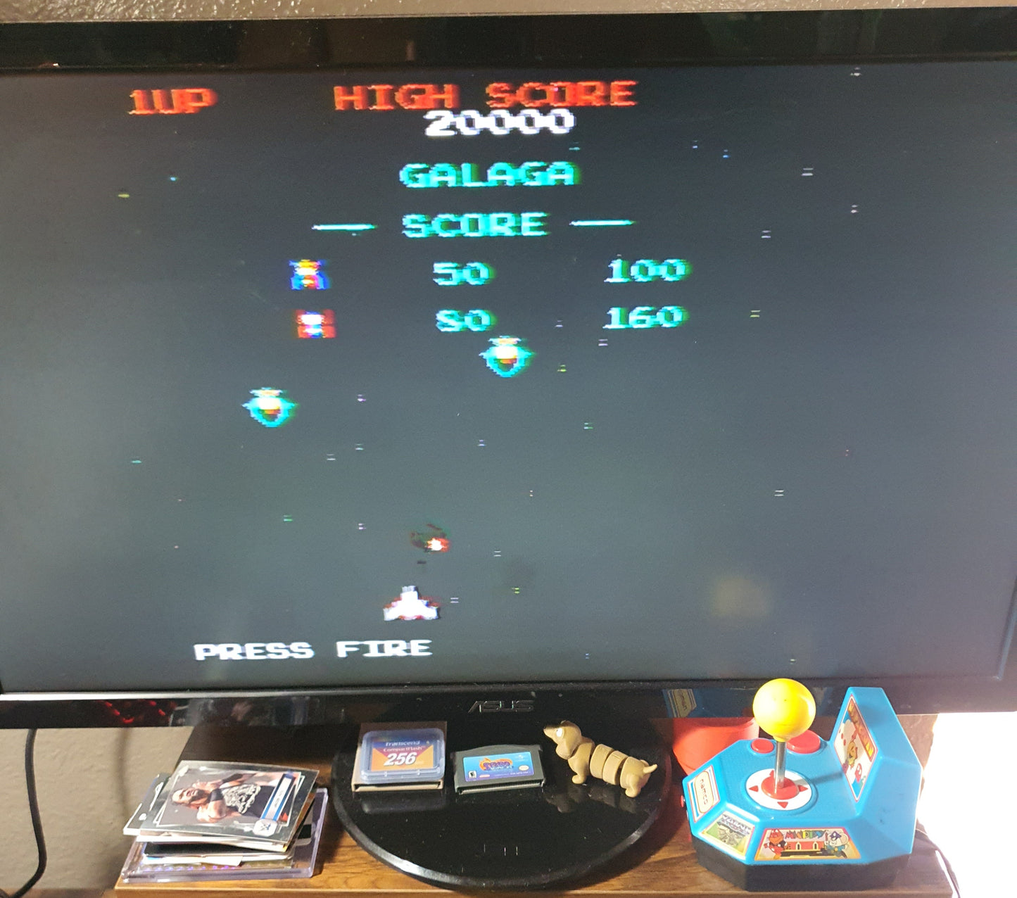 Vintage arcade game display with Galaga on a screen, surrounded by arcade paraphernalia.