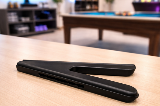 Black pool cue on a pool table with a blurred background of a game room.
