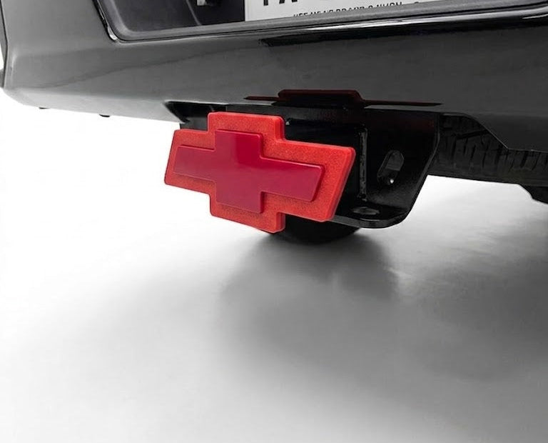 Red hitch cover on a vehicle's hitch receiver with 'TX HITCH' license plate.