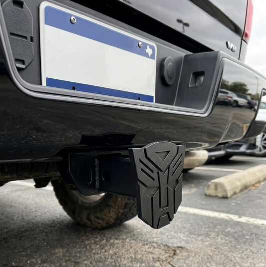Black bumper with a distinctive logo on a vehicle in a parking lot.