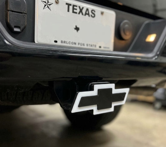 Chevy logo on a vehicle bumper with Texas license plate in the background