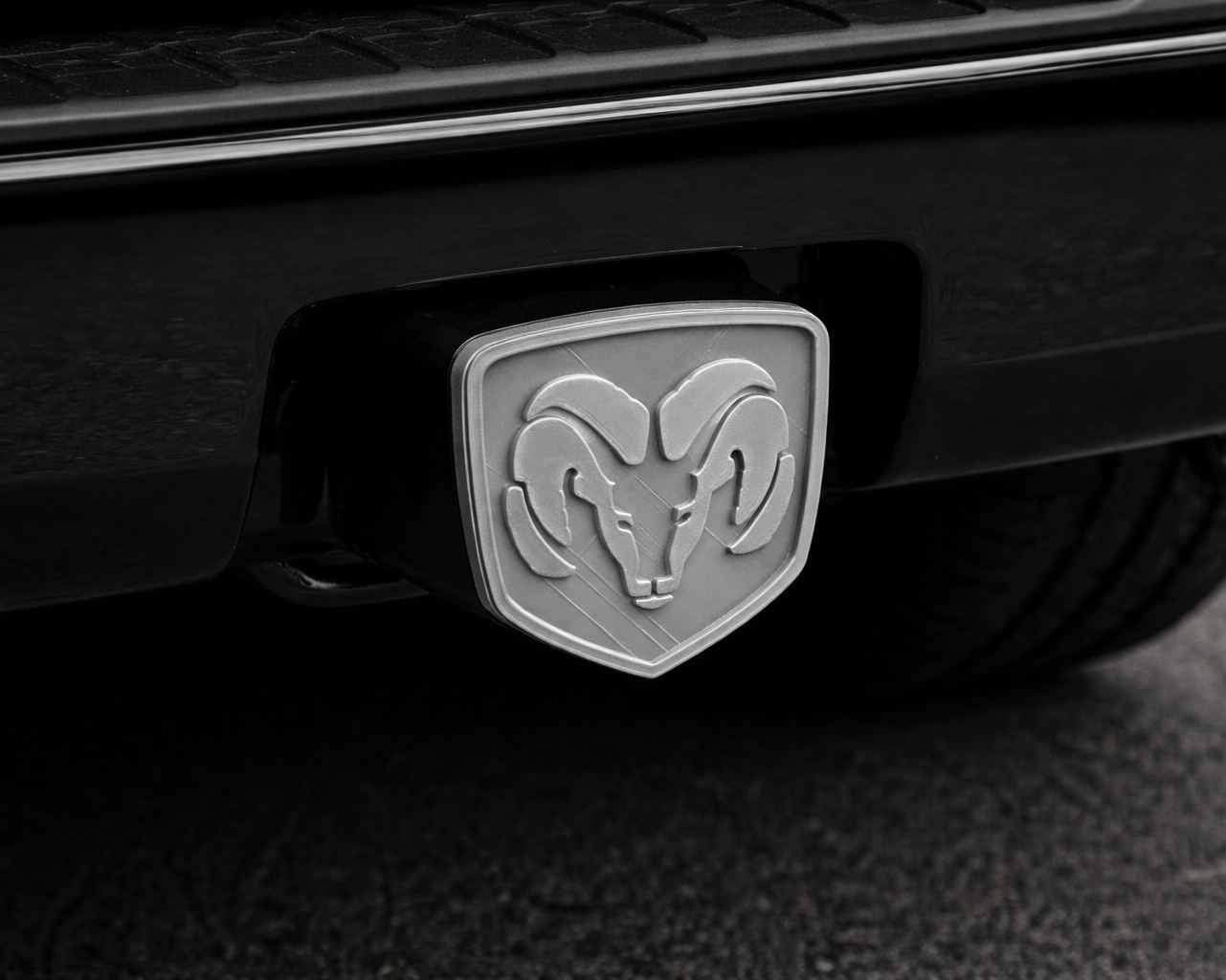 Close-up of a Ram logo on a vehicle's hitch receiver.