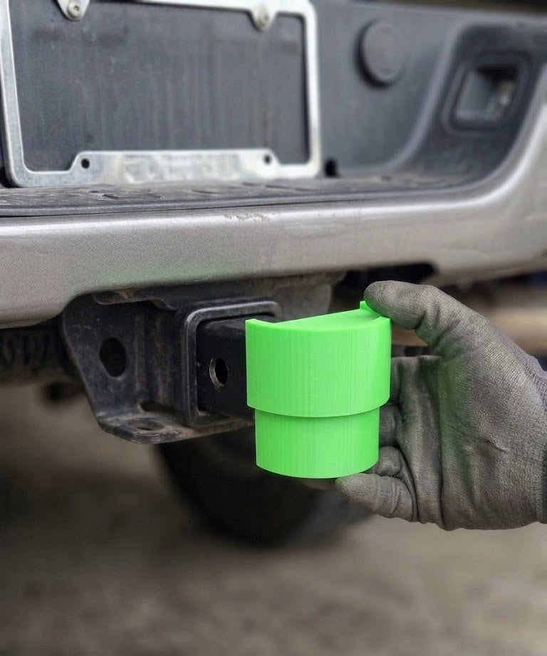 Hand holding a green object near a vehicle's license plate area