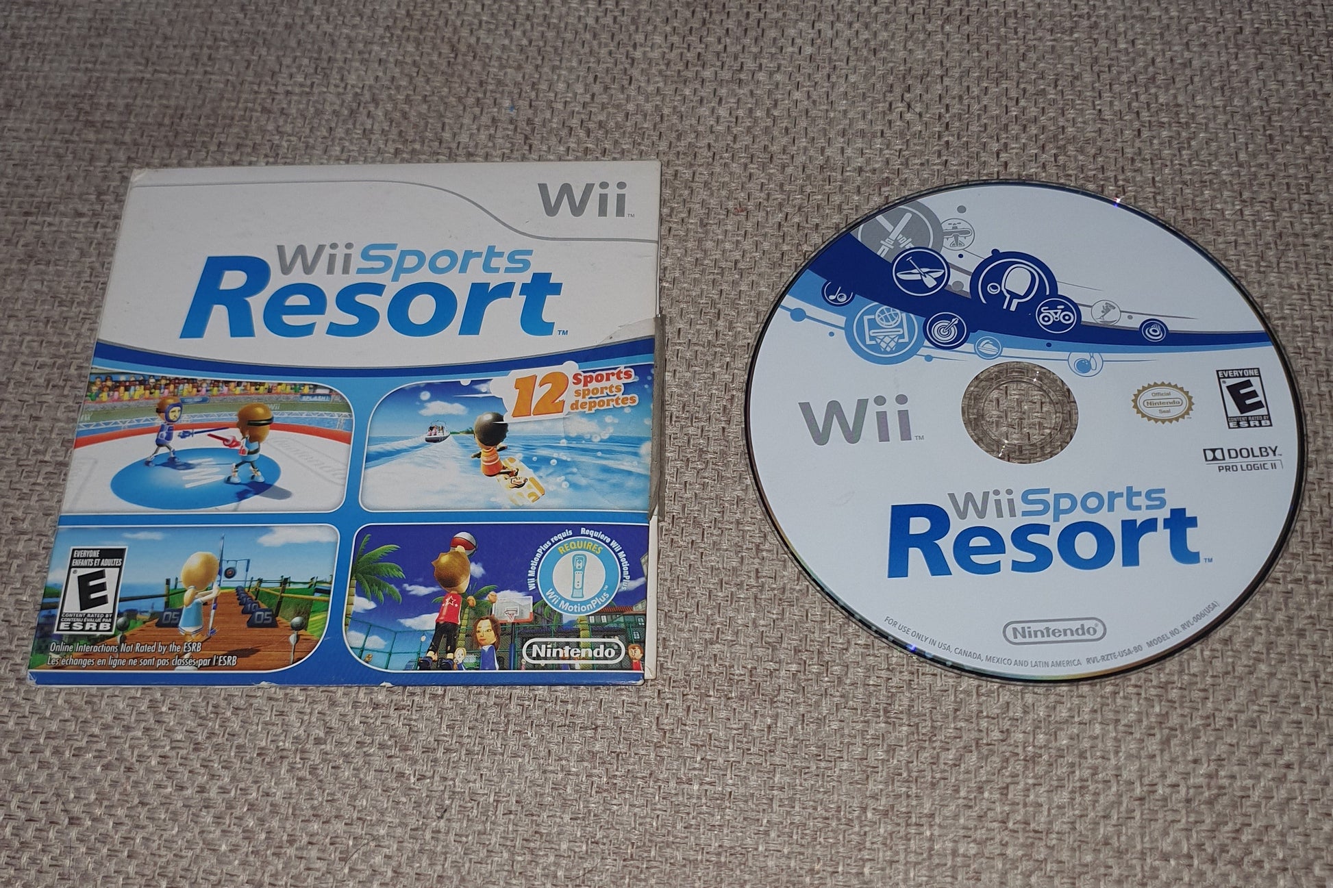 Wii Sports Resort game disc and cover on a textured surface